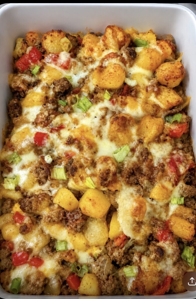 Crispy golden potatoes with ground turkey, red peppers, scallions and melted cheese in a white casserole dish